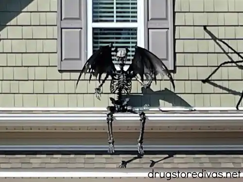 A black skeleton with wings sitting on a roof.