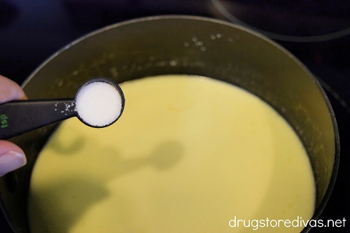 Salt being poured into a pot with cream in it.