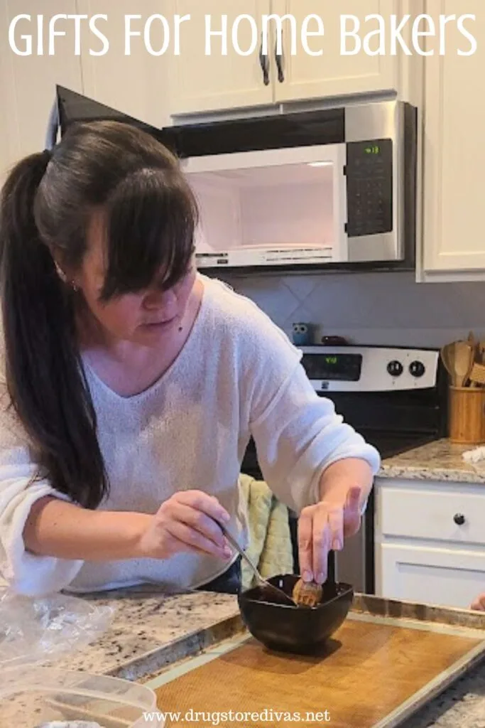 A woman in a white shirt dipping a cookie into a bowl that's on a silicone baking mat-lined baking sheet with the words "Gifts For Home Bakers" digitally written above her.