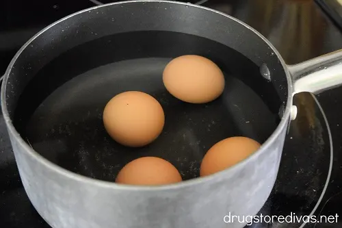 Four eggs in a bowl on a stove.