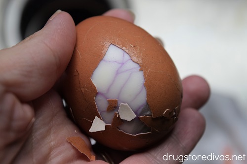 A hard boiled egg with some of the shell pealed back to reveal a spiderweb pattern.