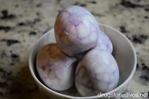 A bowl of hard boiled eggs with a spiderweb pattern on them.