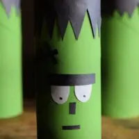 Three toilet paper roll tubes made to look like Frankenstein with the words 