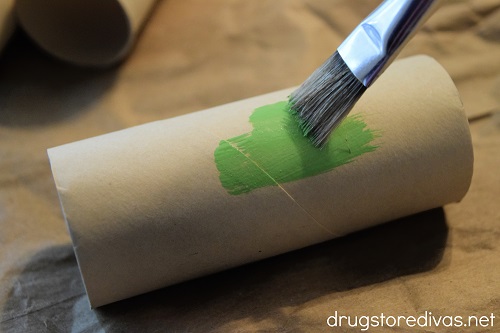 A toilet paper roll being painted green.