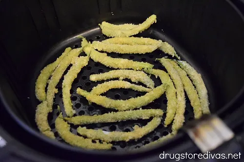Raw panko and parmesan green bean fries in an air fryer.