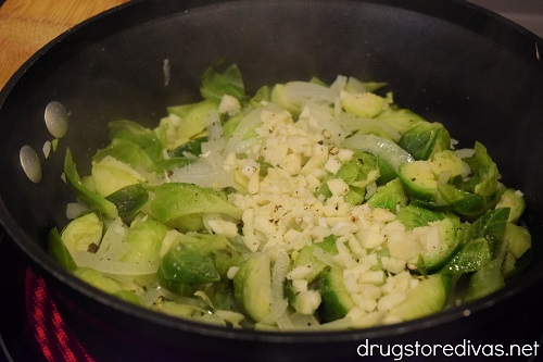 Brussels sprouts, garlic, and onions in a pot.
