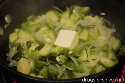Brussels sprouts, garlic, onions, and a pat of butter in a pot.