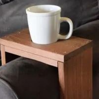 A wooden couch sleeve with a cup in it and the words 