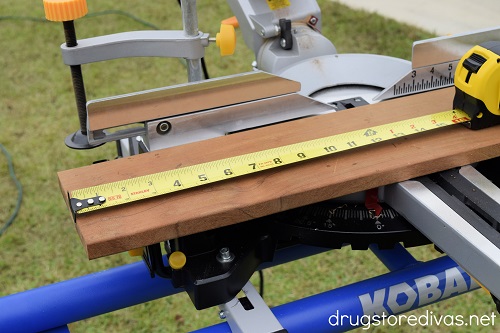 A measuring tape measuring wood on a miter saw.