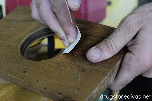 A hand sanding a piece of wood.