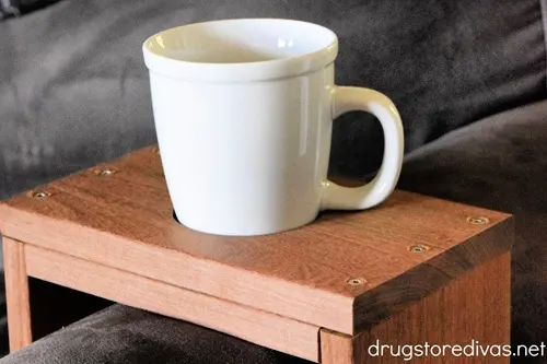 A wooden couch sleeve with a cup and a bag of coffee.