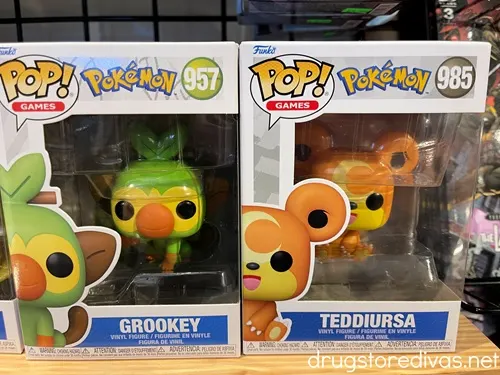 A Grookey and a Teddiursa Pokemon Funko Pop in boxes on a shelf in a store.