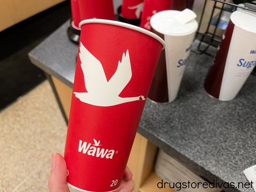 A hand holding a Wawa coffee in store.