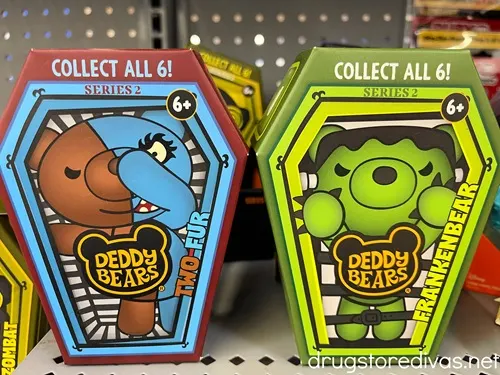 A blue coffin shaped box with a cartoon bear on it next to a neon green coffee shaped box with a cartoon bear on it and both boxes say Deddy Bears.