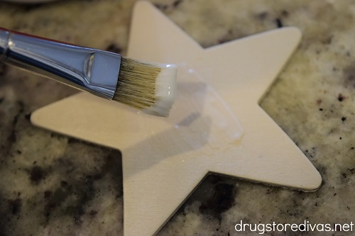 A wooden star being painted with a paint brush.