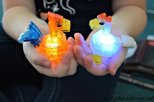 A young child holding two light up building sets that look like a rooster and a chicken.