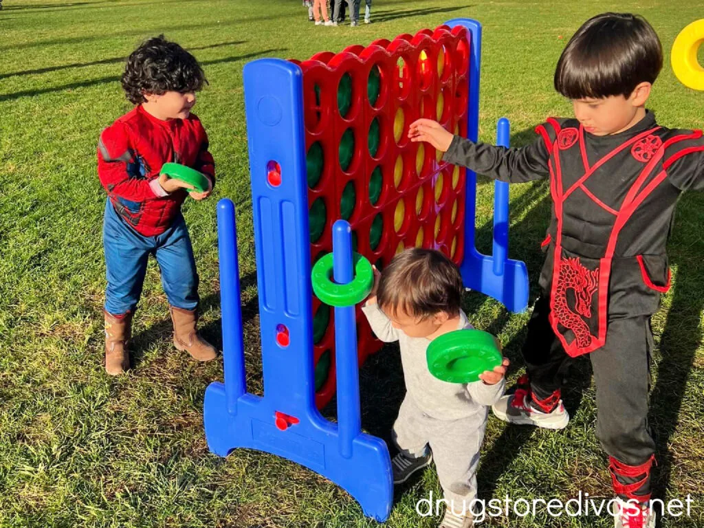 Three boys playing on a gigantic Connect 4.