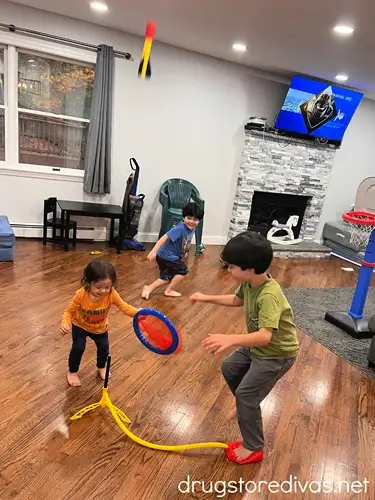 Three boys playing with a Stomp Rocket toy indoors.