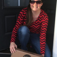 A woman picking up a box at her front door with the words 