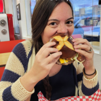 A woman eating a burger in a restaurant with the words 