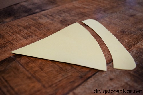 A piece of yellow card stock, in a pizza shape, cut into two pieces.
