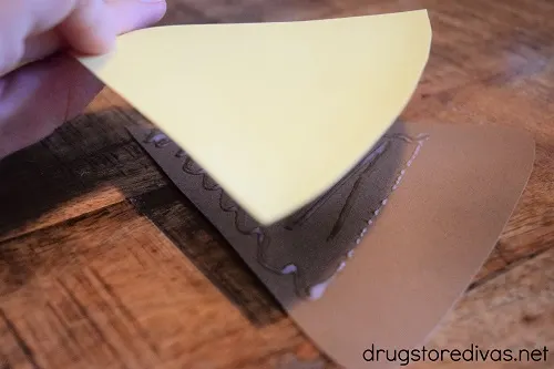 A piece of yellow cardstock being glued to a brown piece of card stock.