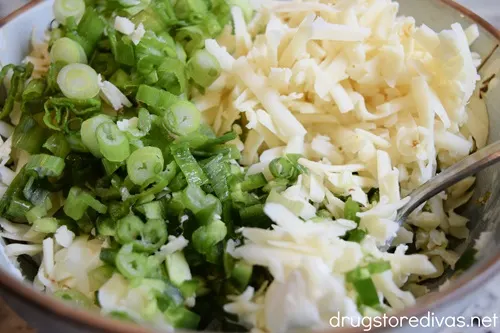 Green onions, white cheese, cream cheese, and chopped jalapeno peppers in a bowl.