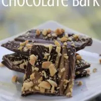 Pieces of chocolate bark with peanuts on it on a plate with the words 