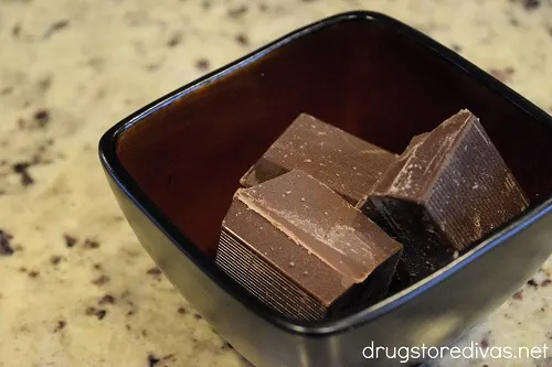 Three squares of chocolate almond bark in a bowl.