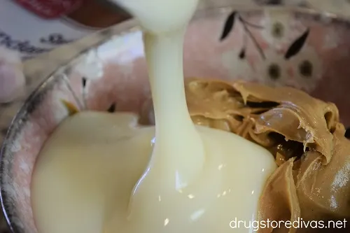 Condensed milk being poured into a bowl of peanut butter.