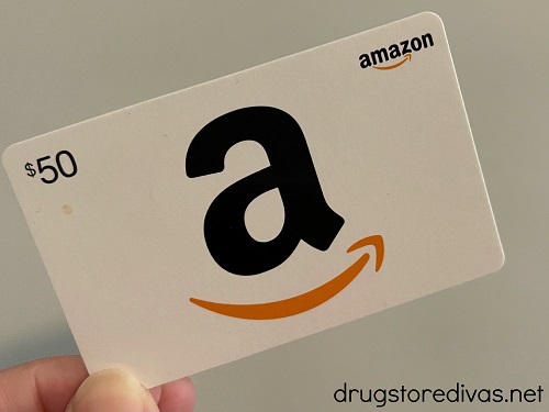 Fingers holding an Amazon gift card.