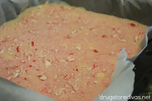 Crushed candy canes on top of pink fudge in a pan.