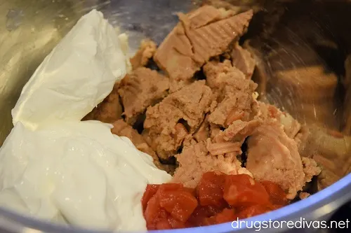 Cream cheese, sour cream, tomatoes, and refried beans in a bowl.