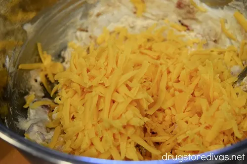 Cheddar cheese on top of other ingredients in a bowl.