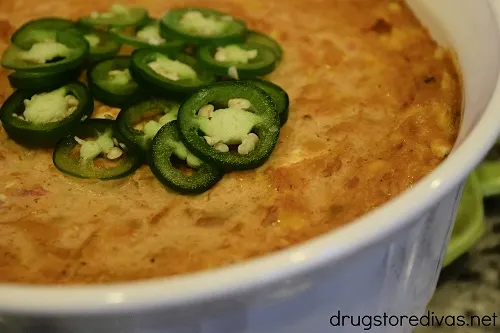 Easy Cheesy Refried Bean Dip, with a sliced jalapeno garnish, in a casserole pan.