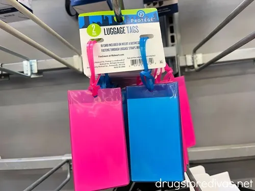 A pack of two luggage tags with a pink luggage tag on the left and a blue luggage tag on the right.