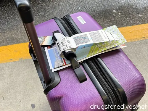Luggage tags on the handle of a purple piece of luggage.