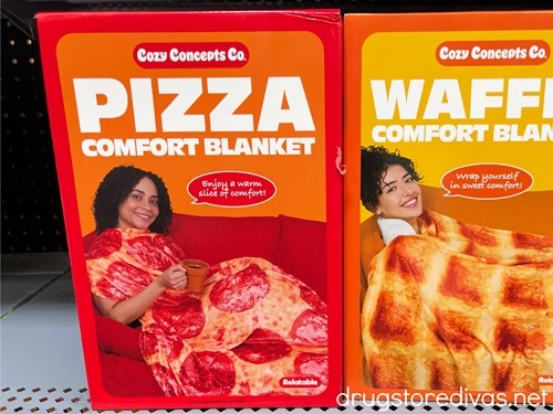 A box with a pizza blanket on a shelf next to a box with a waffle blanket.
