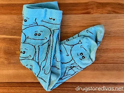 A pair of blue socks with faces drawn on it.