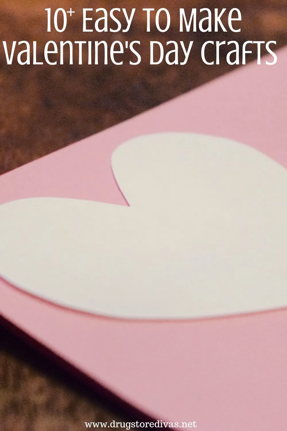 A white heart on top of a pink piece of cardstock with the words 