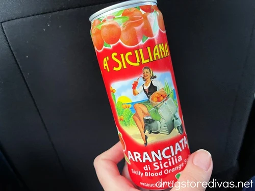A hand holding a can of A Siciliana Soda.