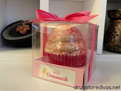 A cupcake shaped bath bomb with two candles behind it.