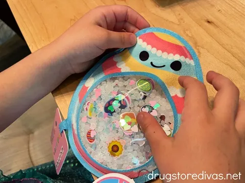 Two kid hands holding an Easter egg-shaped hide and seek bag.