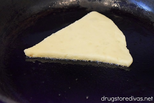 A triangle-shaped piece of dough in a pan.