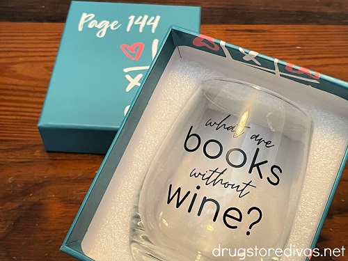 A wine glass in a box that says "what are books without wine?" on it.