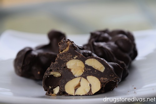 Three chocolate peanut clusters on a white plate.