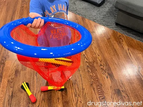 A young boy's hand holding a net with soft rockets in it.