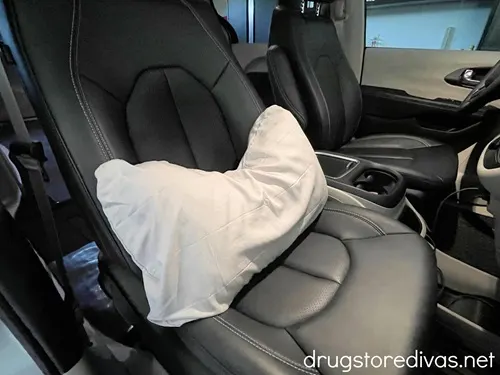 A gray travel pillow in the passenger seat of a mini van.