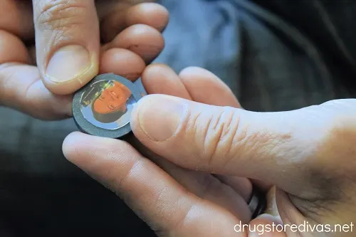 A hand holding a blue circle with a photo of a woman's face on it.