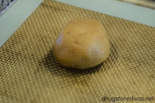 A peanut butter cookie dough ball on a cookie sheet.